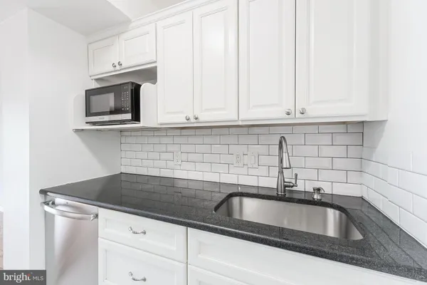 a kitchen with granite countertop white cabinets and a sink