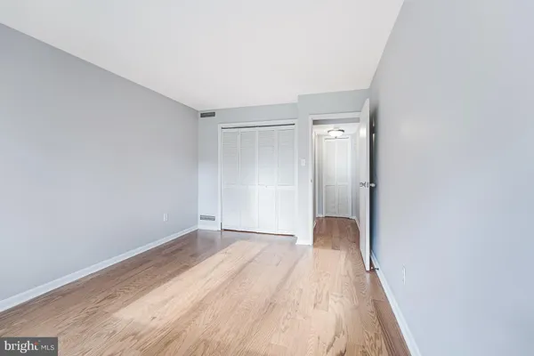 a view of an empty room with wooden floor and closet