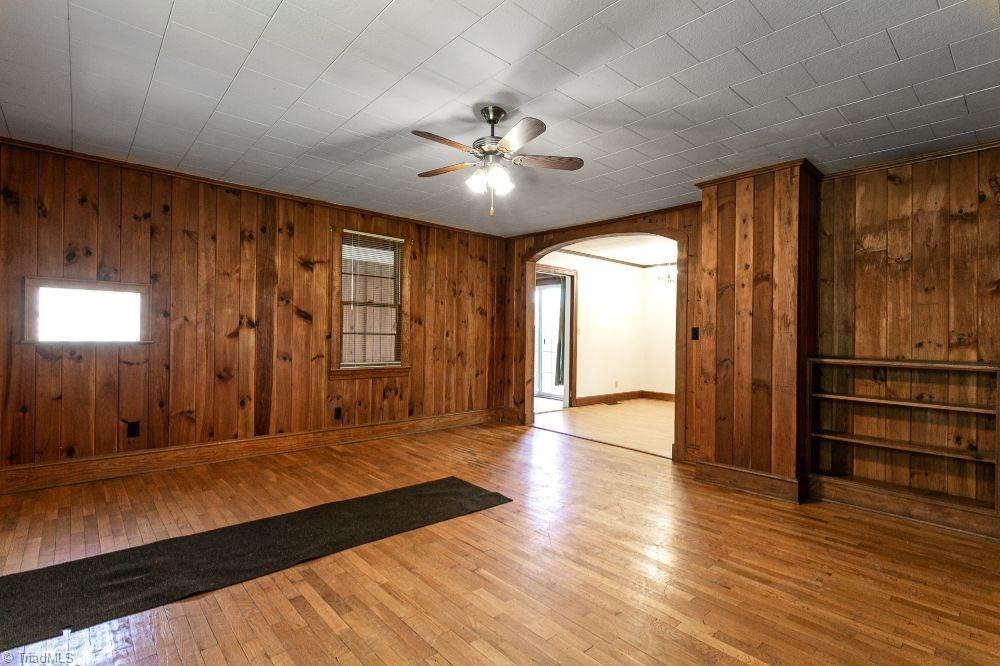 123 Hudson Street Elkin, NC 28621 - Photo 10 of 25 Den features ceiling fan, original wood paneled walls and hardwood floors. Arched doorway leads to dining/kitchen area.