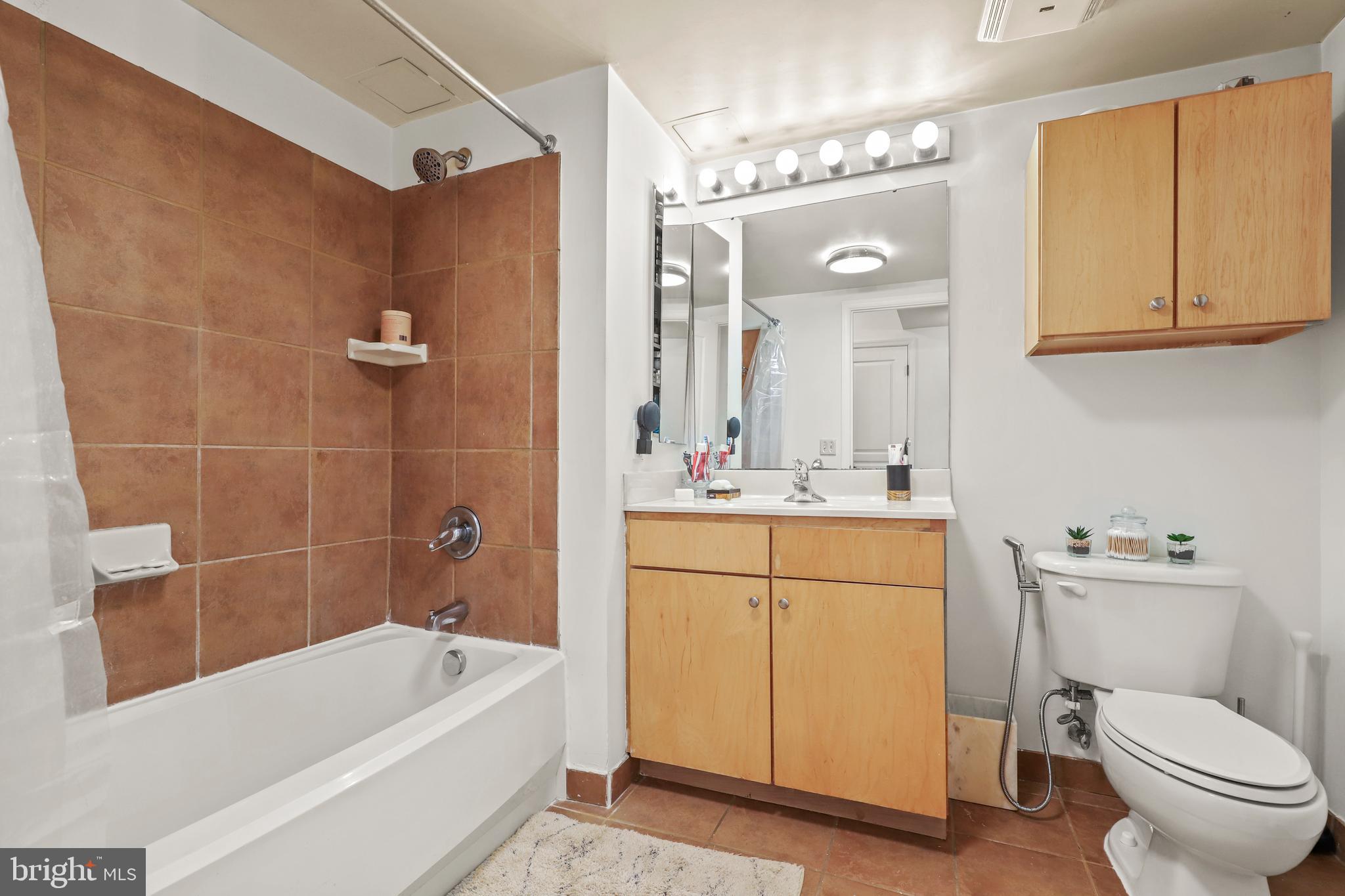 616 E Street Northwest, Unit 1007 Washington, DC 20004 - Photo 18 of 67 a bathroom with a granite countertop sink a toilet and bathtub