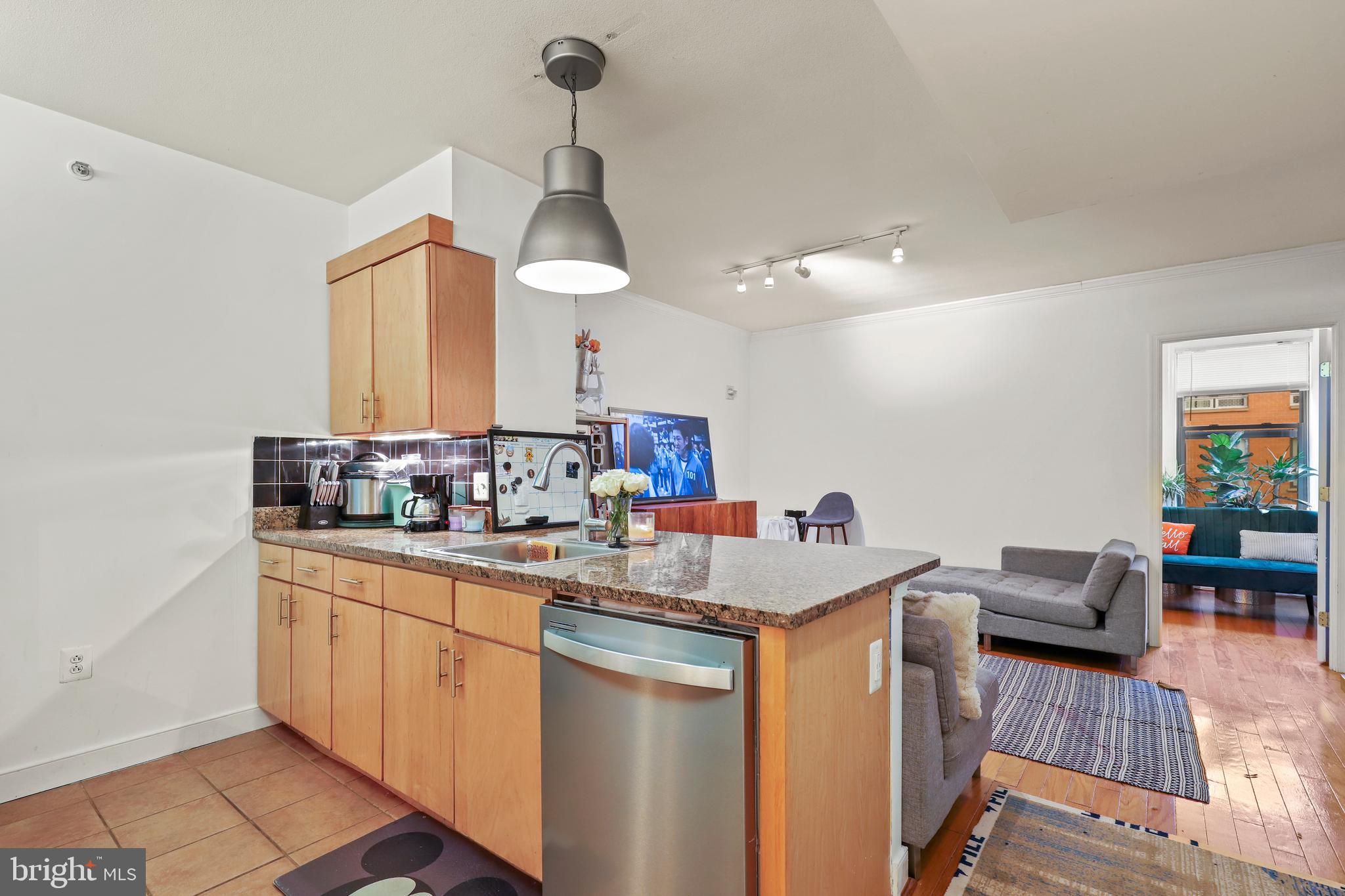 616 E Street Northwest, Unit 1007 Washington, DC 20004 - Photo 5 of 67 a kitchen with a sink dishwasher a dining table and chairs with wooden floor