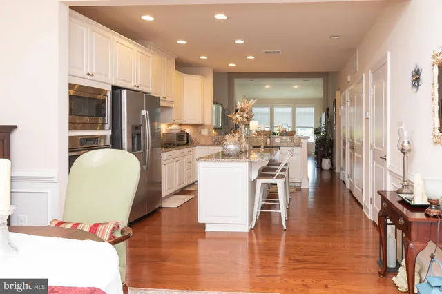 a view of a kitchen with kitchen island white cabinets and stainless steel appliances