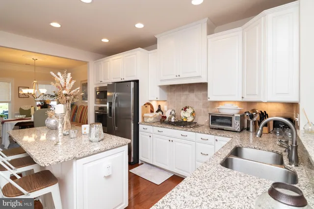 a kitchen with granite countertop a sink a stove and refrigerator