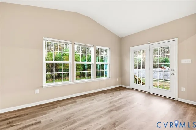 an empty room with wooden floor and windows