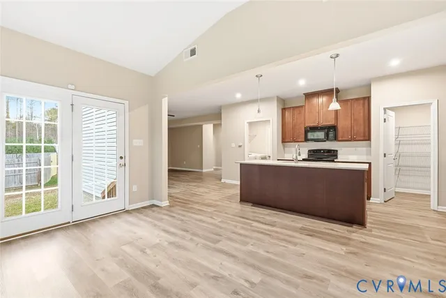 a large kitchen with stainless steel appliances kitchen island granite countertop a stove a sink a refrigerator a cabinets and wooden floor