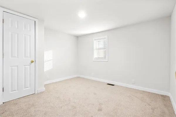 a view of an empty room with wooden floor and kitchen