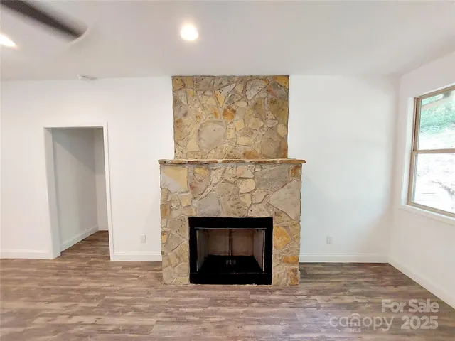 a view of an empty room with wooden floor and a fireplace