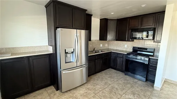 a kitchen with stainless steel appliances granite countertop a refrigerator and a stove top oven