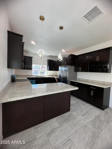 a large kitchen with stainless steel appliances a large counter top a stove a sink a refrigerator and a microwave