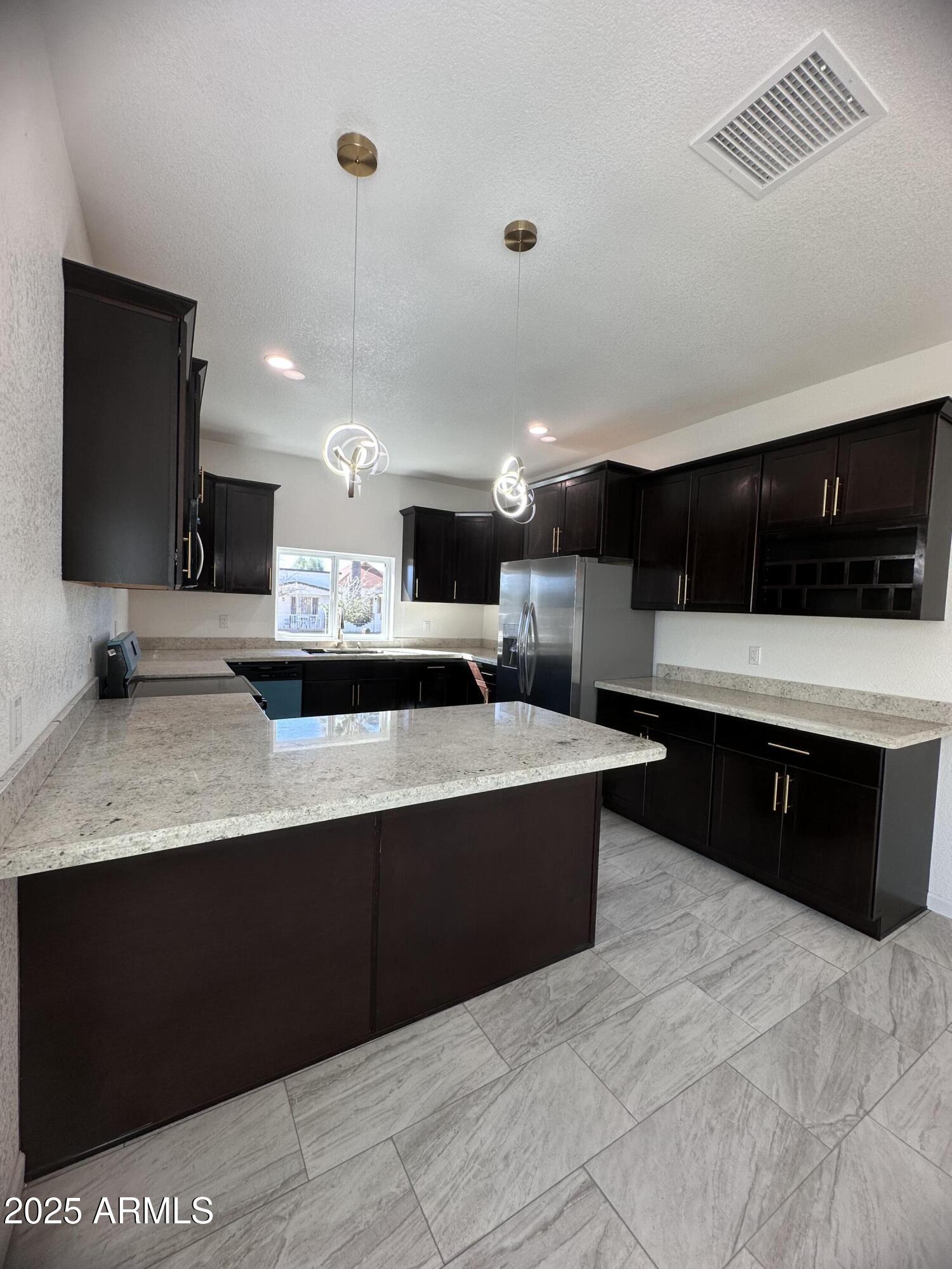 722 East 3rd Street Douglas, AZ 85607 - Photo 3 of 24 a large kitchen with stainless steel appliances a large counter top a stove a sink a refrigerator and a microwave