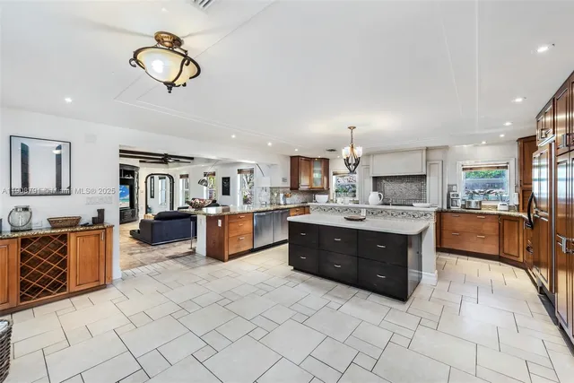 a kitchen with stainless steel appliances kitchen island granite countertop a large counter top a stove a chimney a sink and cabinets