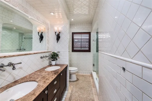 a spacious bathroom with a granite countertop sink a toilet a mirror and shower