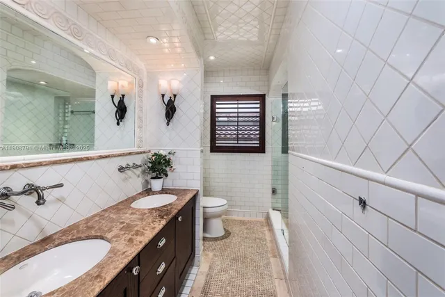 a spacious bathroom with a granite countertop sink a toilet a mirror and shower