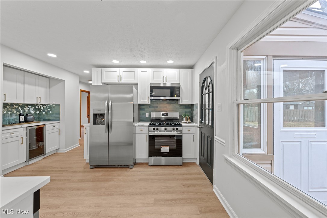 5266 Wilson Mills Road Cleveland, OH 44143 - Photo 17 of 50 Kitchen with appliances with stainless steel finishes, white cabinetry, wine cooler, light wood-style flooring, and recessed lighting