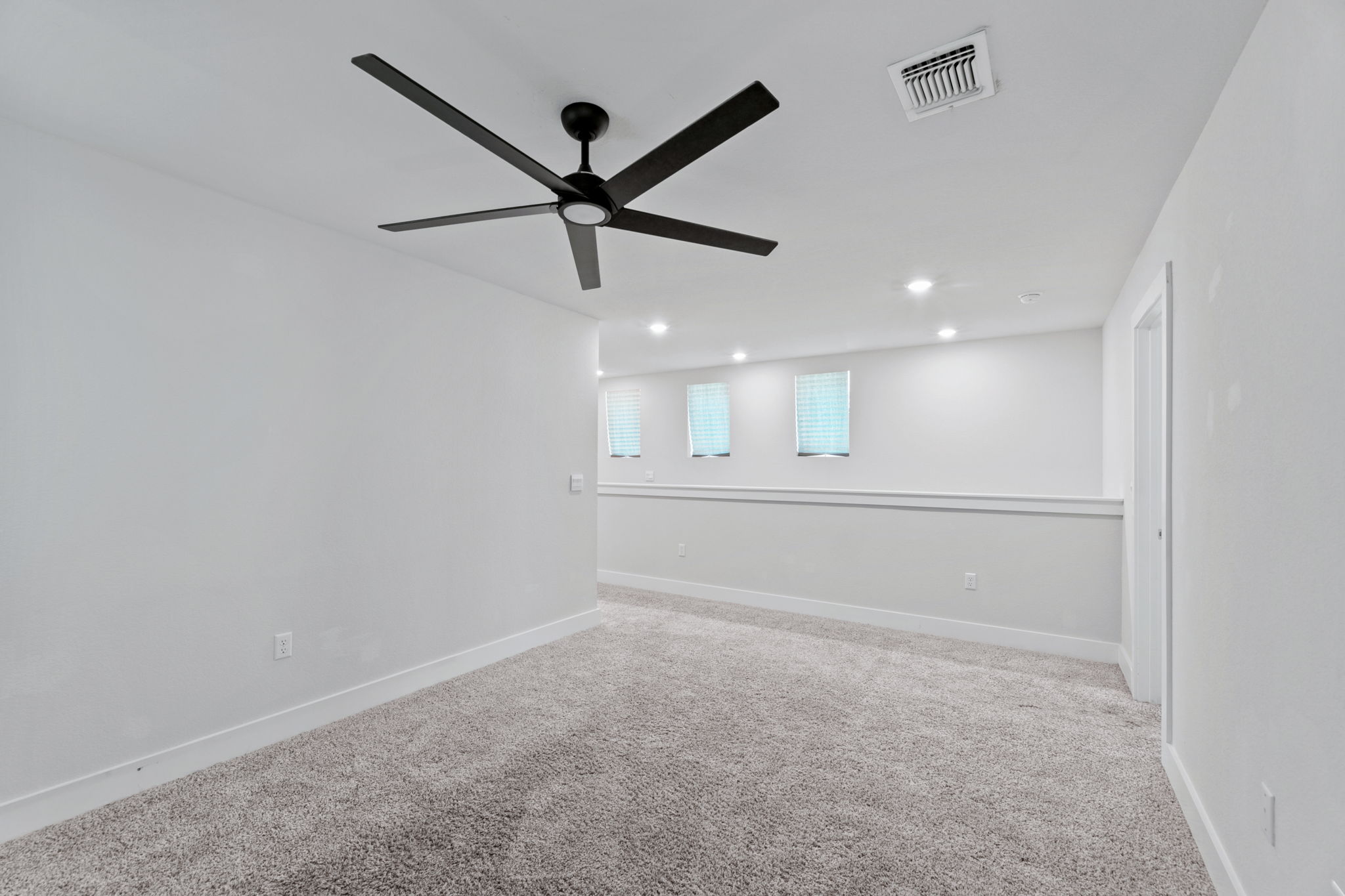 7312 Travertine Spring Drive Austin, TX 78744 - Photo 22 of 32 Well-lit room featuring soft gray carpet and a contemporary ceiling fan, perfect for a cozy retreat.