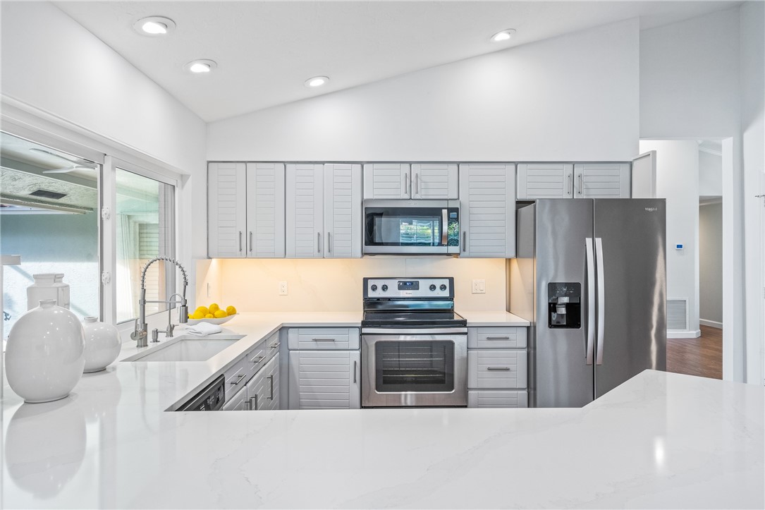 1939 Ocean Ridge Circle Vero Beach, FL 32963 - Photo 22 of 33 a kitchen with stainless steel appliances kitchen island granite countertop a refrigerator and a stove top oven