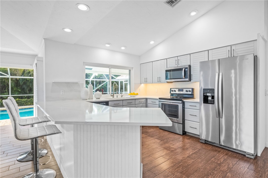 1939 Ocean Ridge Circle Vero Beach, FL 32963 - Photo 23 of 33 a kitchen with stainless steel appliances granite countertop a refrigerator a stove a sink dishwasher a oven with white cabinets and wooden floor