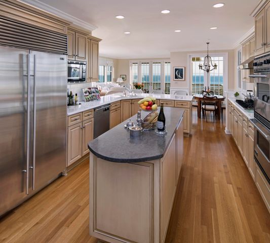 a kitchen with stainless steel appliances granite countertop a refrigerator a stove top oven a sink dishwasher and white cabinets with wooden floor