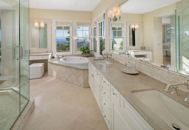a large bathroom with a granite countertop double vanity sink a mirror and a bathtub
