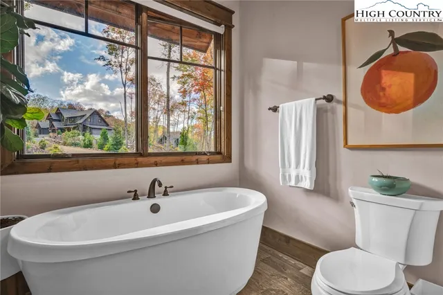 a white bath tub sitting next to a white toilet next to a window