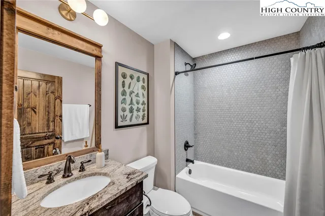 a bathroom with a granite countertop sink toilet a mirror a vanity and shower