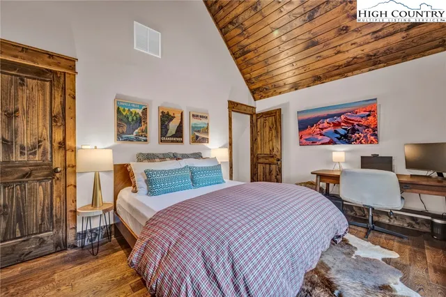 a bedroom with a bed wooden floor and a flat screen tv
