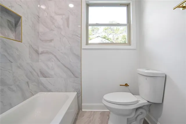 a white toilet sitting next to a bath tub