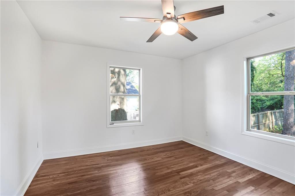 1321 Avon Avenue Southwest Atlanta, GA 30310 - Photo 15 of 20 an empty room with wooden floor chandelier fan and windows