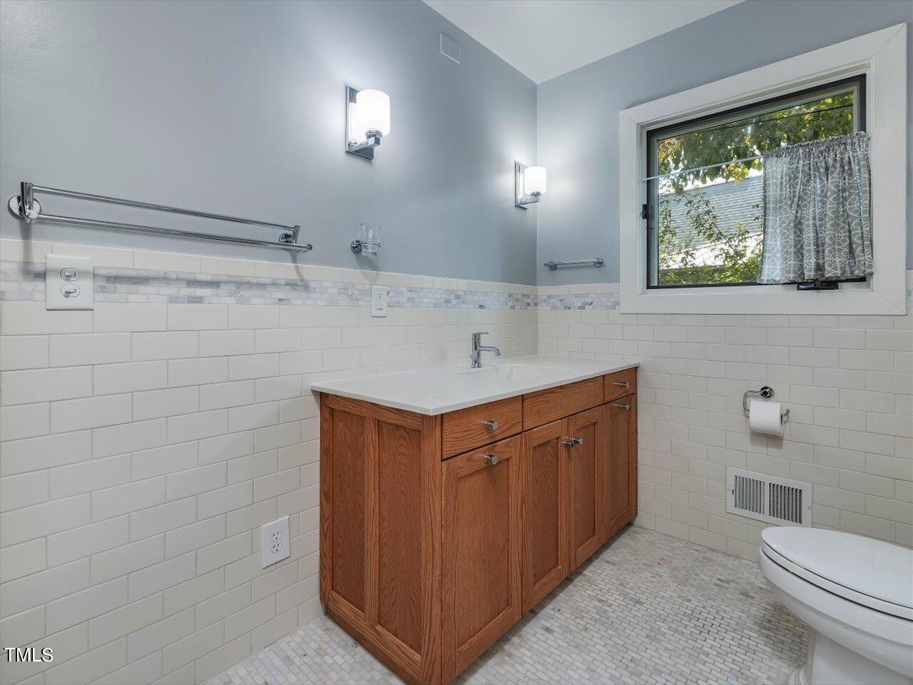 2129 Ridge Road Raleigh, NC 27607 - Photo 52 of 79 a bathroom with a sink a toilet a mirror and a window
