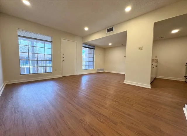 an empty room with wooden floor and windows
