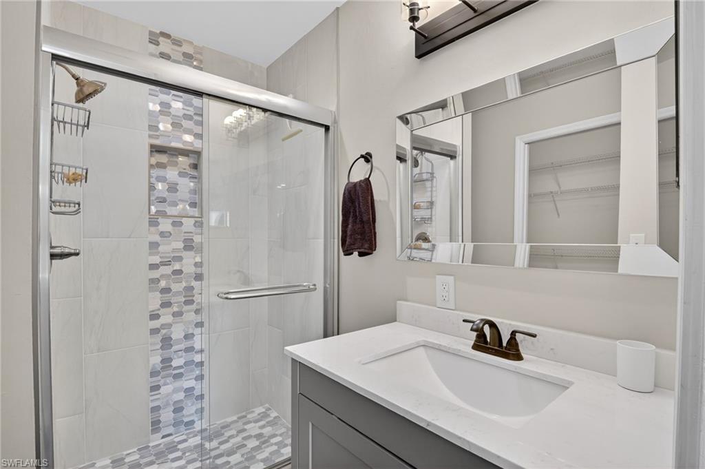 209 Robin Hood Circle, Unit 201 Naples, FL 34104 - Photo 10 of 29 a bathroom with a sink vanity granite shower and a mirror