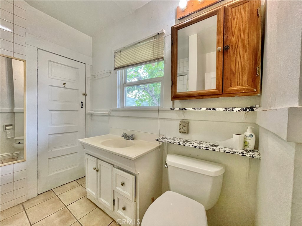 4474 Highland Place Riverside, CA 92506 - Photo 19 of 22 a bathroom with a granite countertop toilet sink and mirror
