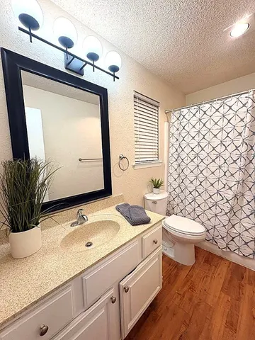 a bathroom with a granite countertop sink mirror vanity and toilet