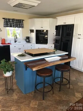 a kitchen with stainless steel appliances kitchen island granite countertop a sink and a refrigerator