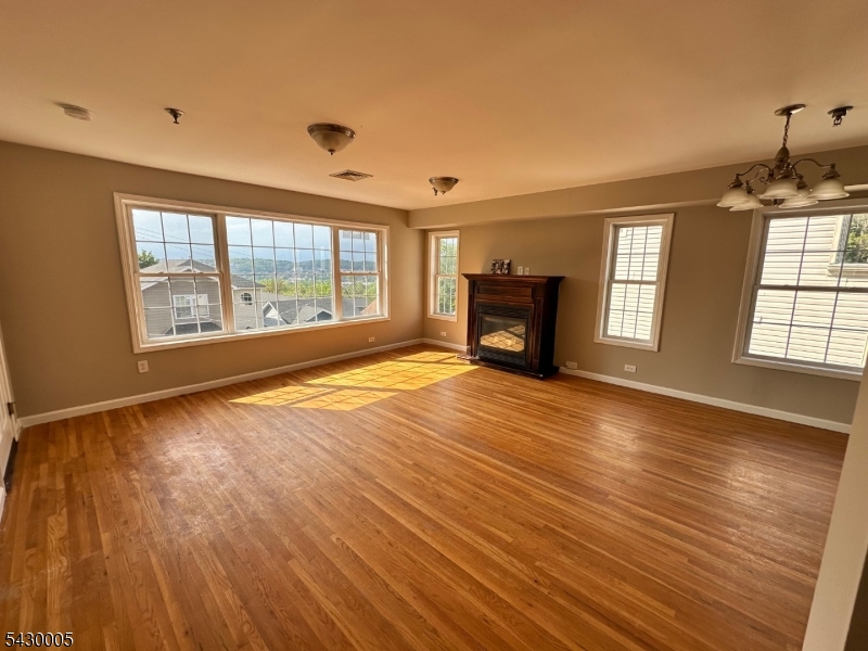 63 Garret Street, Unit 2 Paterson, NJ 07501 - Photo 9 of 9 an empty room with windows fireplace and wooden floor