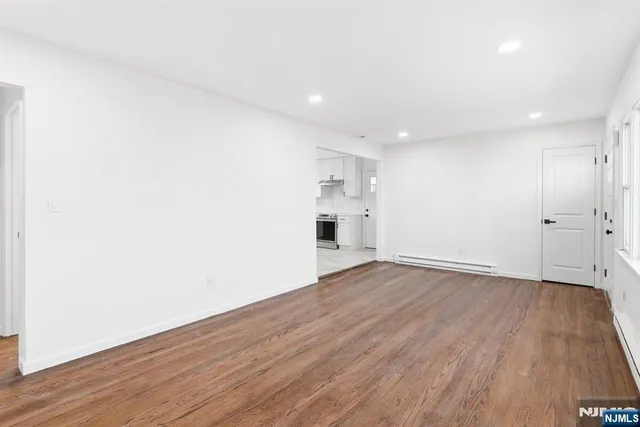 a view of empty room with wooden floor and window