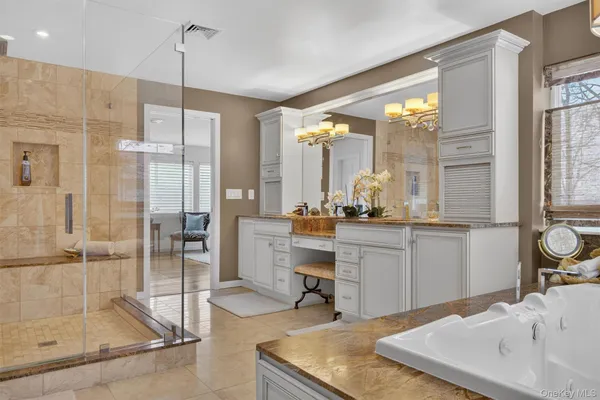 a room with kitchen island a sink and white cabinets next to a window