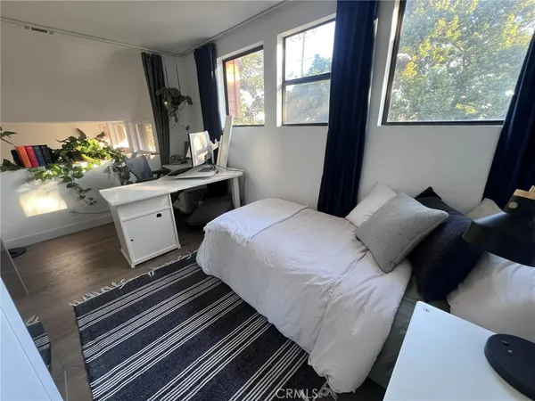 a bedroom with a bed wooden floor and a large window