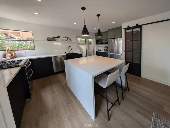 a kitchen with kitchen island a stove a table and chairs in it
