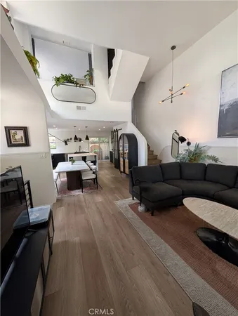 a living room with furniture kitchen view and a wooden floor