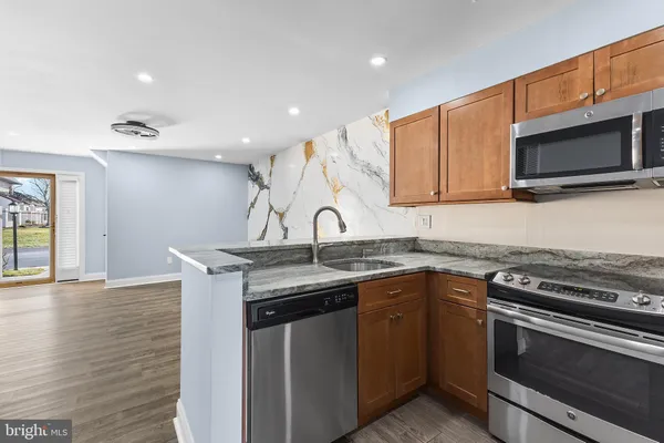 a kitchen with stainless steel appliances granite countertop a sink and a stove top oven with wooden floor