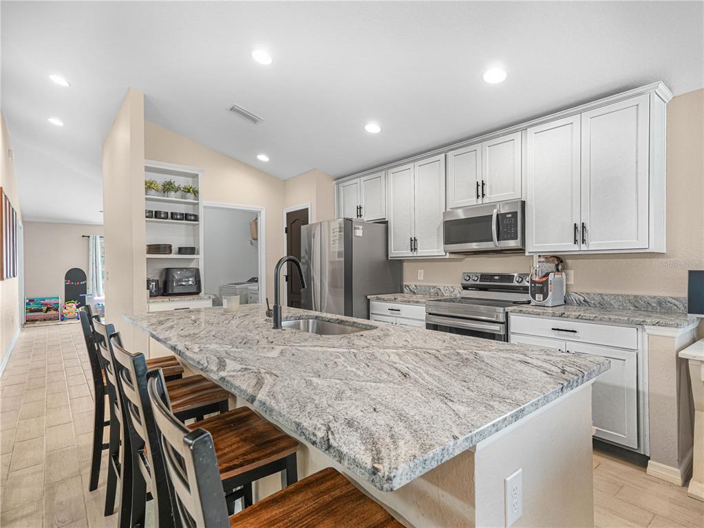 266 South Lake Avenue Frostproof, FL 33843 - Photo 11 of 42 a kitchen with stainless steel appliances granite countertop a stove top oven a sink refrigerator and cabinets