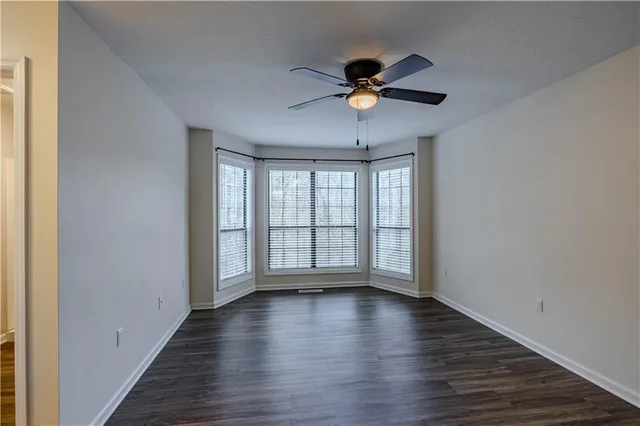 a view of an empty room with window and wooden floor