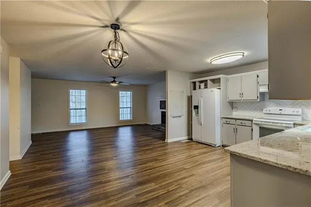 a kitchen with stainless steel appliances granite countertop a refrigerator a sink dishwasher a stove and white countertops with wooden floor