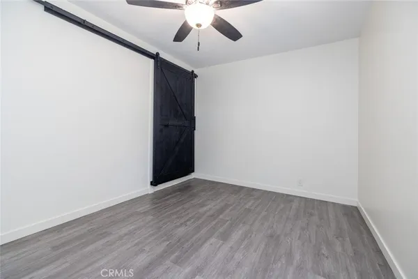 an empty room with wooden floor ceiling fan and window