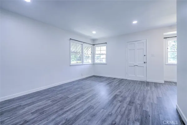 an empty room with wooden floor and windows