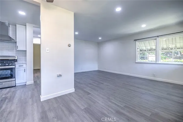 an empty room with wooden floor cabinet and windows