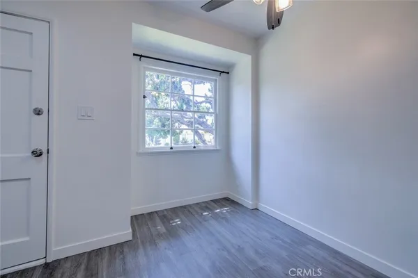 an empty room with wooden floor cabinet and windows