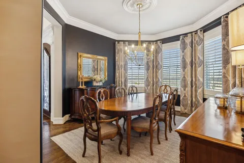 a view of a dining room with furniture large windows and a chandelier