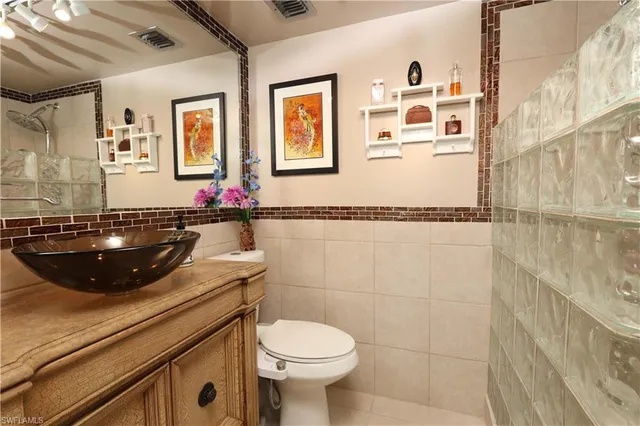 a white toilet sitting next to a bathroom sink and a mirror